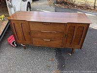 Front view of walnut wood credenza/server showing drawers and doors