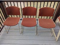 Three Steelcase mid-century chairs with orange fabric seats and backs on metal sled base, front view.
