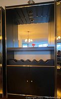 Front view of bar cabinet showing large mirror, gold trim, and wavy wine bottle rack.