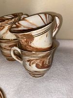 Closeup of two espresso cups stacked, highlighting handmade marbled design and 24KT gold trim.