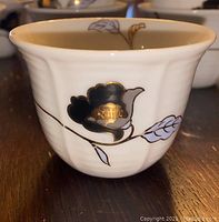 Single porcelain cawa cup showing the detailed black and gold floral and leaf pattern on white porcelain.