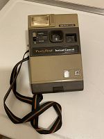 Front view of vintage Kodak Partyflash Instant Camera showing body, lens, flash area, and rainbow strap.