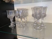 Shelf display of 13 crystal wine glasses in three distinct sizes with intricate cut glass patterns.