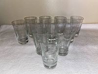 Eleven clear drinking glasses together showing overall condition and style.