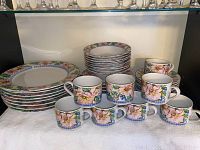 Full set of dinnerware displayed showing stacked plates, bowls, and cups with floral design