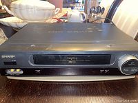 Front view of black Sharp VHS Player with labels and controls visible