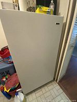 Exterior front view of white upright freezer in room setting
