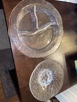 Top view of two decorative frosted glass bowls on a wooden table, one larger with bird design, one smaller with textured pattern.