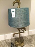Front view of lamp showing brass flamingo base and blue-green drum shade