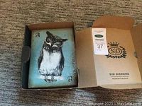 Closed view of the memory block in its opened box showing the owl design with playing card elements.