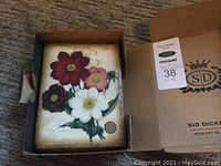 Front view of memory block in original box showing multicolor floral design and metal emblem