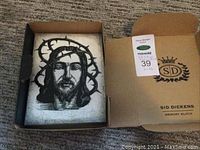 Opened box showing the memory block with the black and white image of a man wearing a crown of thorns.