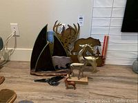 All forest themed decorative items arranged on floor including ceramic bird, wooden animals, metal wall hangings