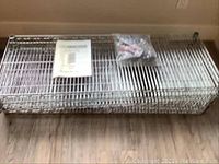 Stacked and folded metal wire shelves with plastic bag containing assembly hardware and a manual on top.