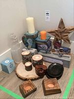 Photo of assorted candle holders, candles, bird sign decor, and other decorative items arranged on floor
