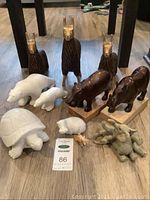 Photo of all animal statuettes showing llamas, polar bears, hippos, rhino, elephants, and turtle on wood floor.