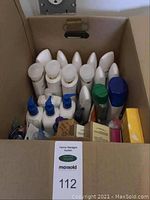 Box with multiple bottles and boxes of personal care products seen from above, mostly white bottles with pump tops and caps.