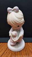 Front view of the Precious Moments porcelain figurine, showing the girl holding the cat in her hands.
