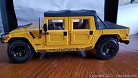 Side view of the yellow and black diecast Hummer model showing details of tires, doors, and soft top roof