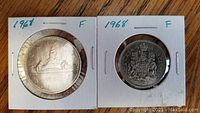 Front and back of the 1968 Canadian one dollar and fifty cent coins in holders, showing reverse designs.