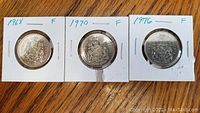 Reverse side of three Canadian fifty cent coins dated 1968, 1970, and 1976 showing the Canadian coat of arms.