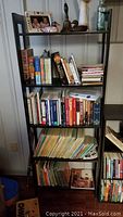 Photo of the 5 shelf bookshelf filled with books and some decorative items to show size and condition.
