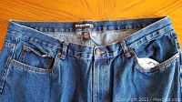 Close-up photo of waistband and pockets of one pair of Roadrunner blue jeans, showing fabric, button, rivets, and tag