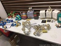 Full view of assorted Christmas ornaments, gift boxes, and light strands on white table