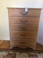 Front view showing dresser with five drawers and decorative metal handles.