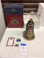 Photo showing the Evil Queen figurine front view with original box and papers on table.