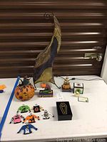 Full lot showing illuminated sculpture, Jim Shore figurines, Quacker Factory sweater ornaments, and Pot Bellys House Haunter box.