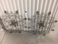 Pair of ornate metal wall decor pieces leaning against a corrugated metal wall, each approximately 32 inches in diameter, showing overall design.