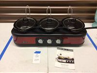 Full unit with 3 removable cooking pots and lids with spoons placed in each pot, showing the front control knobs and Bella brand logo.