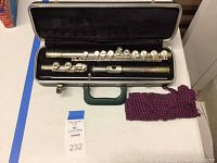 Full view of the Bundy silver flute taken apart in the open case, with cleaning cloth beside it.