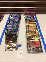 Photo showing various Johnny Lightning die-cast cars arranged on a table, all unopened in blister packs including The Mummy series car, London bus and taxi, and other collectible cars.