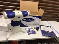 Back2Life massager device on table with packaging box, power adapter, user manual, and comfort mat visible.