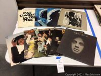 Collection of vintage vinyl records laid out on a table, featuring cover art with various artists including Bob Dylan and Billy Joel.