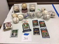 Full view of autographed baseballs in protective cases and loose with baseball cards and packs on table
