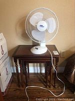 Set of three nesting tables with a white oscillating fan on top.