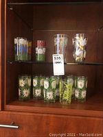 Full view of all 12 glasses in a cabinet, showing grouped floral designs.