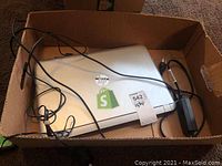 Box containing silver HP Pavilion laptop with power adapter and cables coiled around it