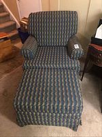 Front view of armchair with ottoman showing striped patterned fabric upholstery in blue, green, and tan colors.