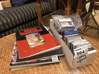 Stack of Sports Illustrated magazines topped with a Michael Jordan Sportsman of the Year issue next to a box of assorted sports cards in plastic sleeves.