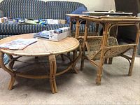Woven rattan round coffee table next to two matching rectangular woven side tables showing overall form and design.