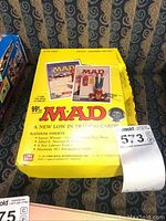 Yellow cardboard box with Mad Magazine branding containing trading cards, showing front and side panels.