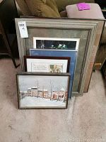 Photo of 5 framed prints and art pieces stacked together showing different frame styles and sizes