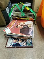 Stack of various vinyl LP records partially inside a reusable shopping bag.