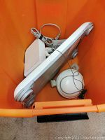 Orange bin containing a white Nintendo Wii console, Wii Balance Board, sensor bar, and cables.