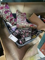 Photo showing a bin with tall floral rubber boots, mid-calf floral rubber boots, black floral ankle boots, black Converse sneaker, purple slip-on sneaker and brown sandals