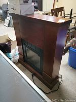 Front angle view of the electric fireplace with wooden mantel, showing overall design and scratches.